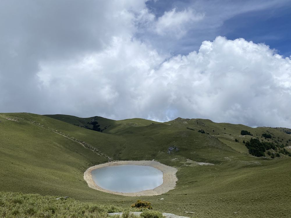 嘉明湖位於翠綠高山草坡間的凹地，上方雲層翻湧