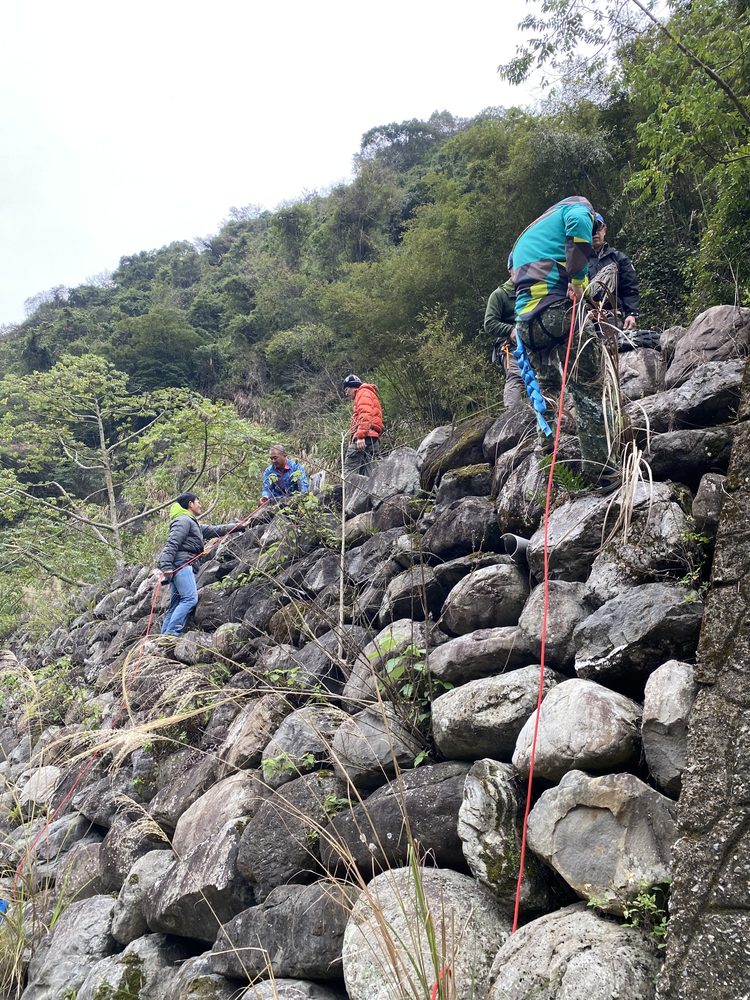 學員在陡峭巨石地形上以繩索確保，逐一通過
